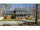 Charming brick home with a welcoming front porch, set amongst a wooded landscape and blue skies at 1500 Allen Ln, Hillsborough, NC 27278