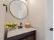 Bathroom featuring a single sink with a wood cabinet, round mirror, and decorative flowers at 153 N Farm Dr, Clayton, NC 27527