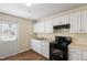 Bright kitchen with white cabinets, black appliances, and door to the outside at 158 Torain St, Hillsborough, NC 27278