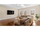 Well-lit living room with hardwood floors, large windows, and a comfortable sectional sofa with throw pillows at 1705 Yates Pond Way, Raleigh, NC 27606