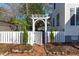 Charming backyard entrance with a white picket fence, pergola, and brick walkway at 202 Duncan St, Raleigh, NC 27608