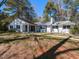 Charming single-story home with a white exterior, covered porch, and lush landscaping, nestled among tall trees at 205 Old Greensboro Rd, Chapel Hill, NC 27516