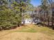 Exterior shot of a white home with lush green lawn and mature trees, offering privacy and curb appeal at 205 Old Greensboro Rd, Chapel Hill, NC 27516