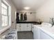 A bright laundry room with modern appliances, white cabinetry, a sink, and patterned tile flooring at 205 Old Greensboro Rd, Chapel Hill, NC 27516