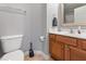 A bathroom featuring a wood cabinet, vanity, white countertop, framed mirror, sink, toilet and tile flooring at 2822 Casona Way, Raleigh, NC 27616