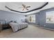 Spacious bedroom featuring a tray ceiling, ceiling fan, and natural light from large windows at 2822 Casona Way, Raleigh, NC 27616
