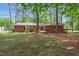The backyard showcases mature trees, green grass, and a brick home with outdoor amenities at 2968 Tram Rd, Fuquay Varina, NC 27526