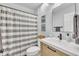 Well-lit bathroom featuring a vanity with modern fixtures, a shower with a striped curtain, and decorative accents at 305 Dickens Rd, Fuquay Varina, NC 27526