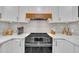 Close-up of the kitchen cooktop with stainless steel appliances, white countertops, and a decorative range hood at 305 Dickens Rd, Fuquay Varina, NC 27526