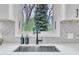 Close-up of modern kitchen sink with decorative fixtures, white quartz countertops, and a view of the backyard at 305 Dickens Rd, Fuquay Varina, NC 27526