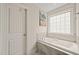 Soaking bathtub with tile surround and a bright window for natural light at 309 Orange Blossom Ct, Wake Forest, NC 27587