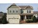 Charming two-story home featuring a mix of sage green siding, brick accents, and an inviting front porch at 309 Orange Blossom Ct, Wake Forest, NC 27587
