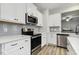 Bright kitchen featuring stainless steel appliances, white cabinets, gray backsplash, and hardwood flooring at 42 Chris Todd Way, Angier, NC 27501