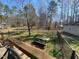 View of the spacious backyard with mature trees, green grass, and a charming picnic table at 55 Waters Edge Loop, Henderson, NC 27537