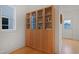 Stylish, built-in light-wood bookcase with glass doors, hardwood floors, and white walls in this lovely living space at 662 Vine Pkwy, Pittsboro, NC 27312