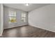 Minimalist bedroom features gleaming hardwood floors, large windows, and a neutral paint color at 717 Tailrace Falls Ct, Wake Forest, NC 27587