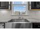 Farmhouse stainless steel sink and granite countertops complement the tiled backsplash and cabinets at 717 Tailrace Falls Ct, Wake Forest, NC 27587