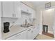 Bright kitchen featuring white cabinets, subway tile backsplash, and stainless steel double sink at 7305 Sandy Creek Dr, Raleigh, NC 27615