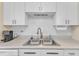 Clean kitchen boasts white subway tile backsplash, updated sink fixtures, and sleek, white cabinetry at 7305 Sandy Creek Dr, Raleigh, NC 27615