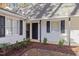 Entrance view with white siding, black shutters and door, complemented by tidy mulch beds and greenery at 1001 Atchison St, Garner, NC 27529