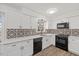 Updated kitchen featuring white cabinets, black appliances, modern backsplash, and bright natural light at 1001 Atchison St, Garner, NC 27529