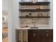 Modern bar area with dark cabinetry, stone backsplash, shelving, counter and a wine refrigerator at 1001 Welch Ln, Raleigh, NC 27614