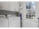 Bright laundry room featuring a washer, dryer, storage cabinets, and a window for natural light at 101 Weatherly Pl, Cary, NC 27518