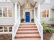 Inviting front entrance with brick steps, white railings, and a blue front door adorned with a floral wreath at 104 Manchester Pl, Chapel Hill, NC 27516