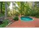 Backyard view featuring a tranquil kidney-shaped pool surrounded by lush greenery and a brick patio at 112 Trellingwood Dr, Morrisville, NC 27560