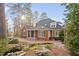 Idyllic backyard featuring a brick patio, well-maintained landscaping, and a tranquil pond surrounded by mature trees at 112 Trellingwood Dr, Morrisville, NC 27560