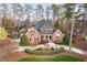 Traditional brick home with a circular driveway, mature trees, and well-maintained landscaping at 112 Trellingwood Dr, Morrisville, NC 27560