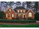 Elegant brick home with manicured front lawn and stately trees in the background at 112 Trellingwood Dr, Morrisville, NC 27560