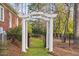 Charming garden gate with white pillars and a black iron fence, surrounded by lush landscaping at 112 Trellingwood Dr, Morrisville, NC 27560