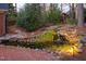 Tranquil backyard with lighted water feature, stone path, and lush greenery at 112 Trellingwood Dr, Morrisville, NC 27560