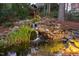 Illuminated stone waterfall cascading into a lush pond, surrounded by natural vegetation at 112 Trellingwood Dr, Morrisville, NC 27560