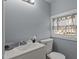 This half bath features a sink, toilet, and a window with natural light, enhanced by the neutral blue wall color at 1855 W West River Rd, Franklinton, NC 27525