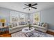 Well-lit living room featuring two sofas, two large windows, and a ceiling fan at 1855 W West River Rd, Franklinton, NC 27525