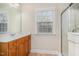 Bathroom with vanity and sink under a large mirror, next to a glass enclosed shower and window at 205 Quarryrock Rd, Holly Springs, NC 27540