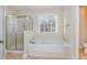 Bright bathroom featuring a shower and separate tub, as well as a window bringing in natural light at 205 Quarryrock Rd, Holly Springs, NC 27540