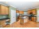 Well-lit kitchen features wooden cabinets, stainless steel appliances, and a kitchen island with lots of room to move at 205 Quarryrock Rd, Holly Springs, NC 27540