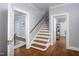 Traditional home hallway featuring hardwood floors, stairs with wooden banister, and neutral paint color at 205 W Markham Ave, Durham, NC 27701