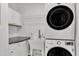 Convenient laundry room with stacked washer and dryer, utility sink and white cabinets at 207 Lewey Brook Dr, Cary, NC 27519