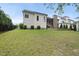 Spacious backyard featuring a stone wall, lush green lawn, and a screened-in porch at 2073 Amalfi Pl, Apex, NC 27502