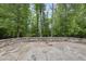 Expansive stone patio featuring a stylish retaining wall and a tranquil wooded backdrop at 2073 Amalfi Pl, Apex, NC 27502