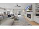 Bright living room with fireplace, TV, built-ins, ceiling fan, and access to kitchen and entry at 2073 Amalfi Pl, Apex, NC 27502