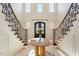 Grand foyer with a curved staircase, marble table, and intricate ironwork at 212 Whirlaway Ln, Chapel Hill, NC 27516