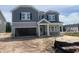 Two-story home with gray siding, stone accents, an attached two-car garage, and an unfinished front yard at 230 Tidal Pool Way, Cary, NC 27519