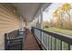 Relaxing covered porch featuring wooden bench and red lounge chair overlooking the serene backyard at 3012 Optimist Farm Rd, Apex, NC 27539