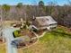 Aerial view showcasing the home's setting, lush landscaping, outdoor fireplace, and proximity to a forested area at 3227 Morrow Farm Ln, Chapel Hill, NC 27516
