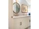 Bathroom vanity featuring an oval mirror, framed artwork, and white cabinetry at 3227 Morrow Farm Ln, Chapel Hill, NC 27516